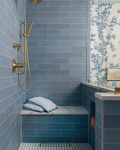 a blue tiled bathroom with a shower head and hand held faucet in the corner