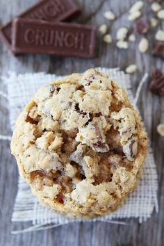 a chocolate chip cookie sitting on top of a piece of paper next to some nuts