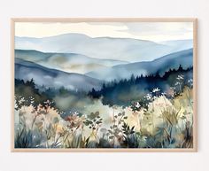 a watercolor painting of mountains and flowers in the foreground, framed on a white wall