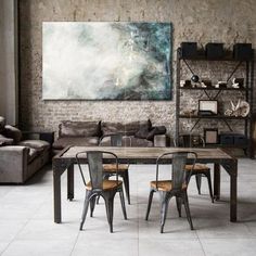 a living room filled with furniture and a wooden table surrounded by metal chairs next to a brick wall