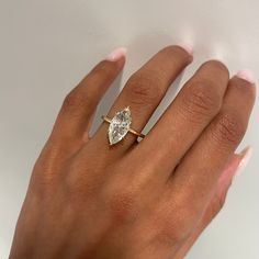 a woman's hand with a diamond ring on top of her finger and the other hand holding an engagement ring