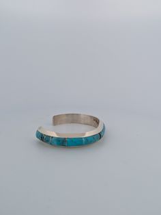 New Native American handmade sterling silver and turquoise inlay cuff bracelet. Petite sterling inserts between flush inlay blue turqouise by Navajo artist Brandon Early Experience the artistry of Native American jewelry with this exquisite handmade sterling silver cuff bracelet featuring intricate turquoise inlay work. Crafted by renowned Navajo artist Brandon Early, this piece showcases petite sterling silver inserts that beautifully complement the flush inlay blue turquoise. The intricate details and high-quality materials make it a unique and timeless accessory. Perfect for adding a touch of Southwestern elegance to your ensemble. PERFECTION. EVERY TIMEAt Rob Sherman Designs, we believe in the beauty of the imperfectly perfect. Our pieces are handcrafted with meticulous care, ensuring Cuff Bracelets Handmade, Turquoise Bracelet Cuff, Turquoise Cuff, Sterling Silver Cuff Bracelet, Kingman Turquoise, Timeless Accessories, Sterling Silver Cuff, Silver Cuff Bracelet, Silver Cuff