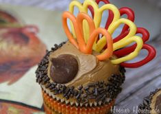 a cupcake decorated like a turkey with thanksgiving decorations on it's head and the words, thanksgiving cupcakes