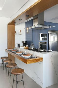 a kitchen with blue cabinets and white countertops, wooden stools and an island