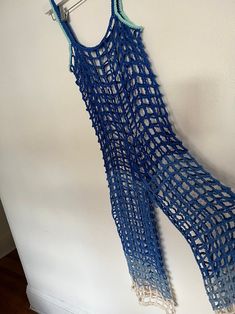 a blue crocheted vest hanging on a wall