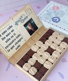 a wooden box filled with chocolates next to an old fashioned card board game controller