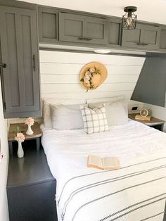 a bed with white sheets and pillows in a bedroom next to a wall mounted light