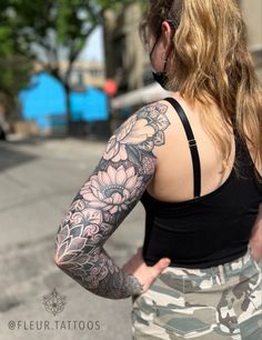 a woman with tattoos on her arm and shoulder is looking down the street while wearing camo shorts