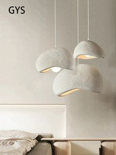 three lights hanging from the ceiling above a bed in a room with white walls and furniture