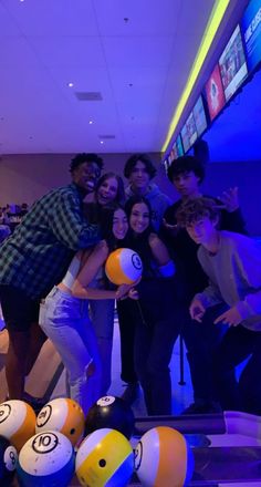 a group of young people posing for a photo with bowling balls in front of them