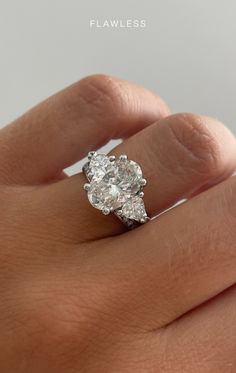 a woman's hand holding an engagement ring with two diamonds on it, and the middle