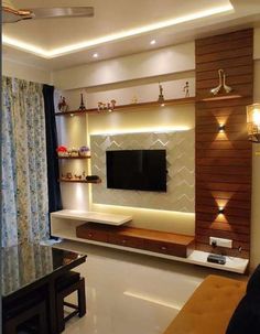 a living room with a flat screen tv mounted on the wall and shelves above it