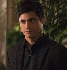 a young man in a black shirt and blazer looking at the camera with an intense look on his face