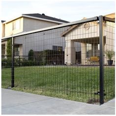 a fenced in yard with a house behind it and grass on the other side