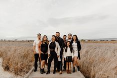 a group of people standing on top of a wooden platform in front of tall grass