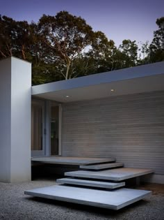 three concrete steps in front of a white building with trees in the background at night