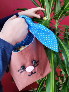 a child's hand is holding a bag with a cat face on it