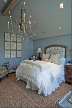 a bed room with a neatly made bed and a chandelier hanging from the ceiling