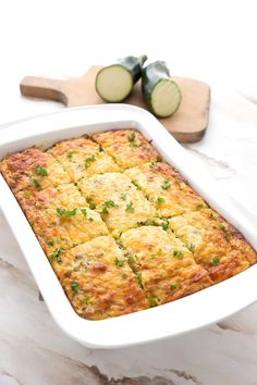 a casserole dish with zucchini and cheese in it on a marble table