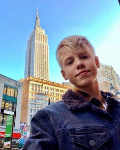 a young man standing in front of a tall building