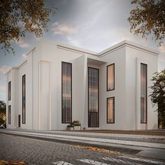 a white building with black windows on the front and side of it, sitting on a cobblestone street