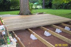 the deck is being built with plastic bags and bottles on it in front of a tree