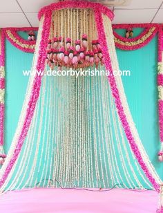 a bed covered in pink and white flowers next to a wall with hanging decorations on it