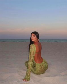 a woman is sitting on the sand at the beach