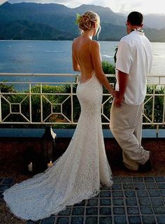 the bride and groom are looking out over the water from their balcony overlooking the mountains