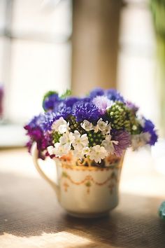 a white cup filled with purple and white flowers