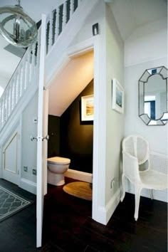 an open door leading to a bathroom with a toilet and mirror on the wall above it