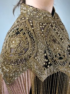 Shaak cape is a masterpiece with its shimmering gold beads and intricate embroidery throughout. The gold beaded fringe adds an extra layer of sophistication to this already exquisite piece. The golden beads used in the design are of the highest quality and glimmer with every movement of the wearer. The embroidery is beautifully crafted and adds texture and depth to the cape. The attention to detail is evident in every inch of this cape, making it a true work of art. Features: Beaded Tassel Hem C Gold Shawl For Festive Evening, Gold Shawl For Festive Evening Events, Gold Shawl For Evening And Festive Occasions, Festive Gold Shawl For Evening, Festive Sequin Shawl, Festive Evening Gold Shawl, Festive Evening Embroidered Shawl, Festive Embroidered Evening Shawl, Festive Embroidered Shawl For Evening