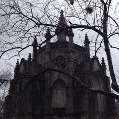 black and white photograph of an old building with trees in front of it on a cloudy day