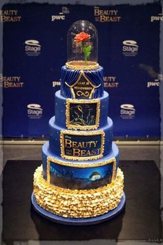 there is a three tiered blue cake with gold decorations on the bottom and sides