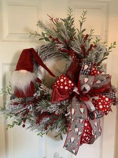 a christmas wreath on the front door with santa's hat and stockings hanging from it