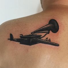 a man with a tattoo on his back has a black and white image of an old record player