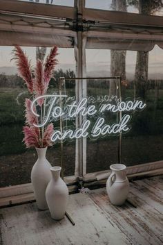 two white vases sitting next to each other on top of a window sill