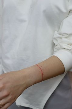 a woman wearing a white shirt is holding her arm with a red line on it