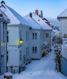 a snowy street lined with white houses in the evening light, surrounded by snow covered rooftops