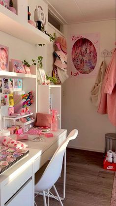 a white desk topped with lots of clutter next to a wall covered in pictures