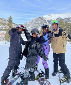 four snowboarders posing for a photo in the mountains