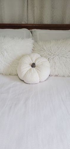 a white bed with two pillows on top of it and a pillow that is shaped like a pumpkin