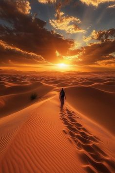 a person walking across a desert at sunset