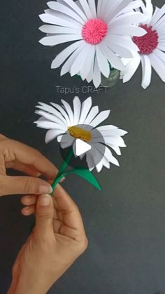 someone is holding up some paper flowers to make it look like they are floating