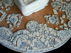 blue and white plates sitting on top of a wooden table next to a vase with flowers