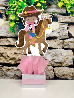 a paper cutout of a girl riding a horse on top of a pink box