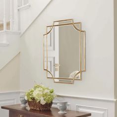 a table with flowers and a mirror on it in a room that has stairs leading up to the second floor