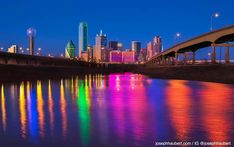 the city skyline is reflected in the water at night with lights reflecting off it's surface