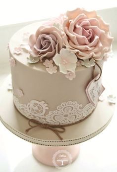 a wedding cake decorated with pink roses and lace