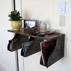 there is a wooden shelf with pictures on it and a cell phone sitting on top